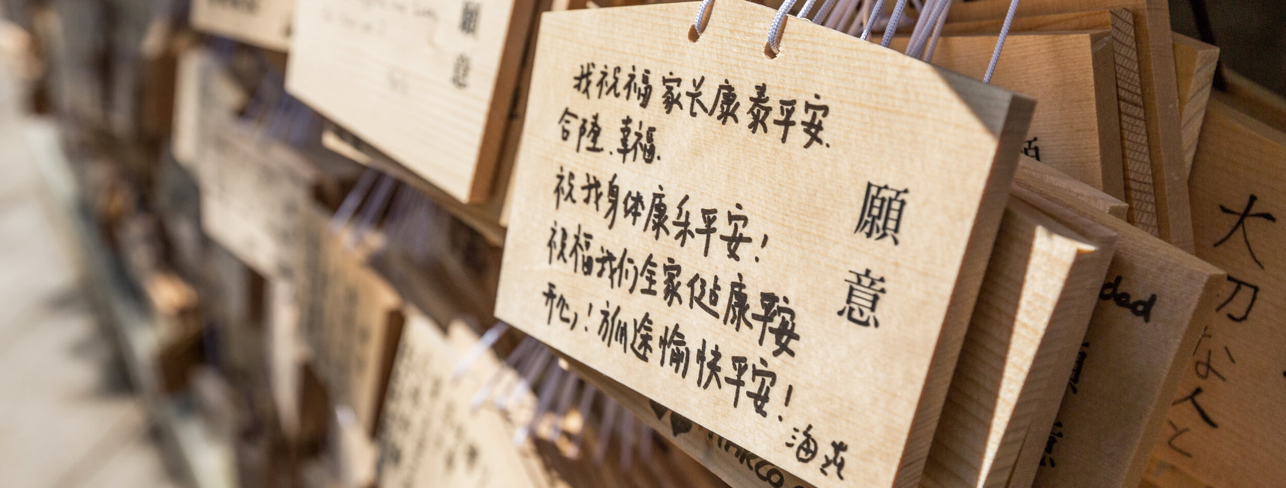 TOKYO, JAPAN - AUGUST 16TH 2015. Prayers written on wooden card called ema in Japanese language at the Meiji Shinto Shrine, Shibuya, Japan.