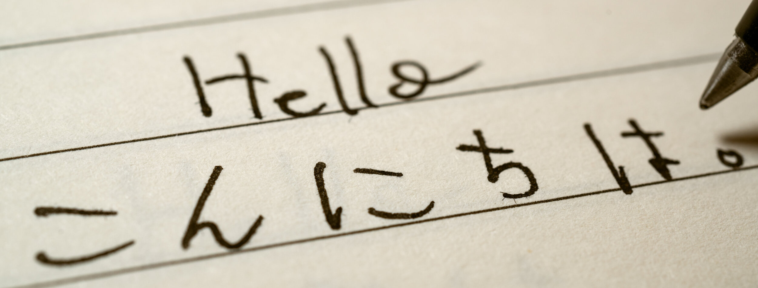 Beginner Japanese language learner writing Hello word in Japanese hiragana characters on a notebook close-up shot