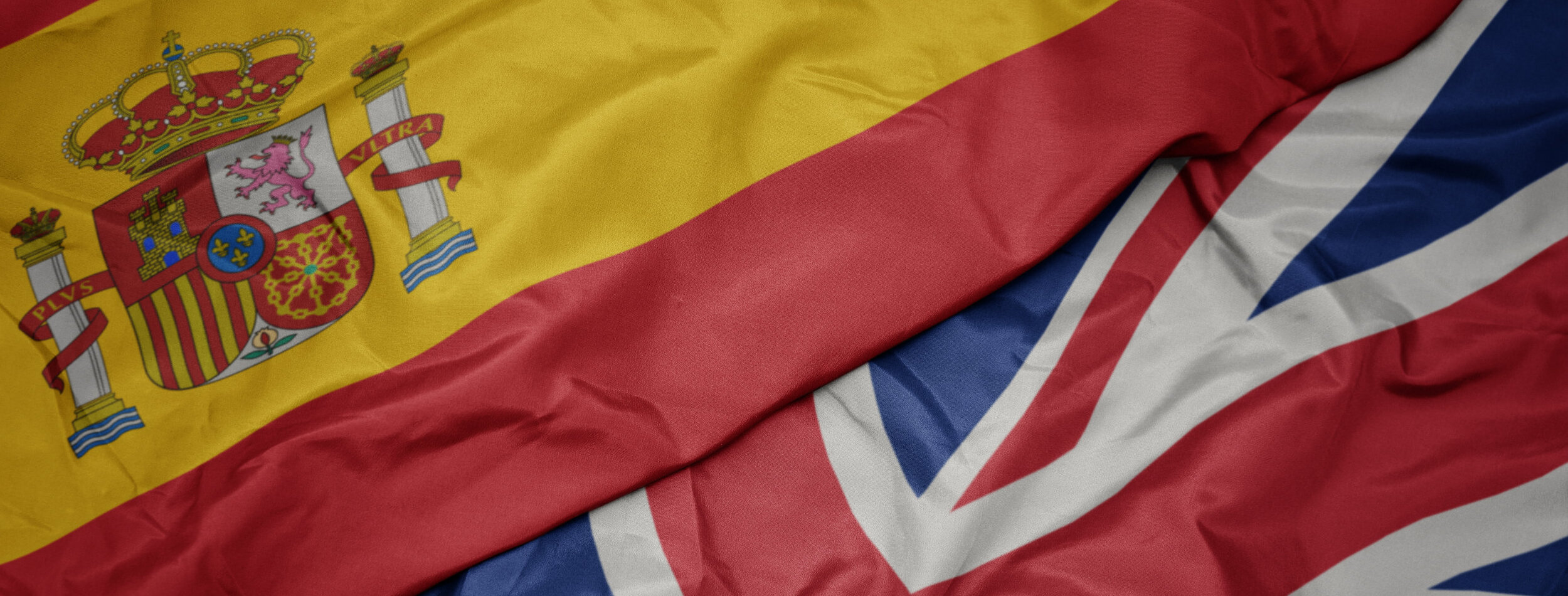 waving colorful flag of great britain and national flag of spain. macro