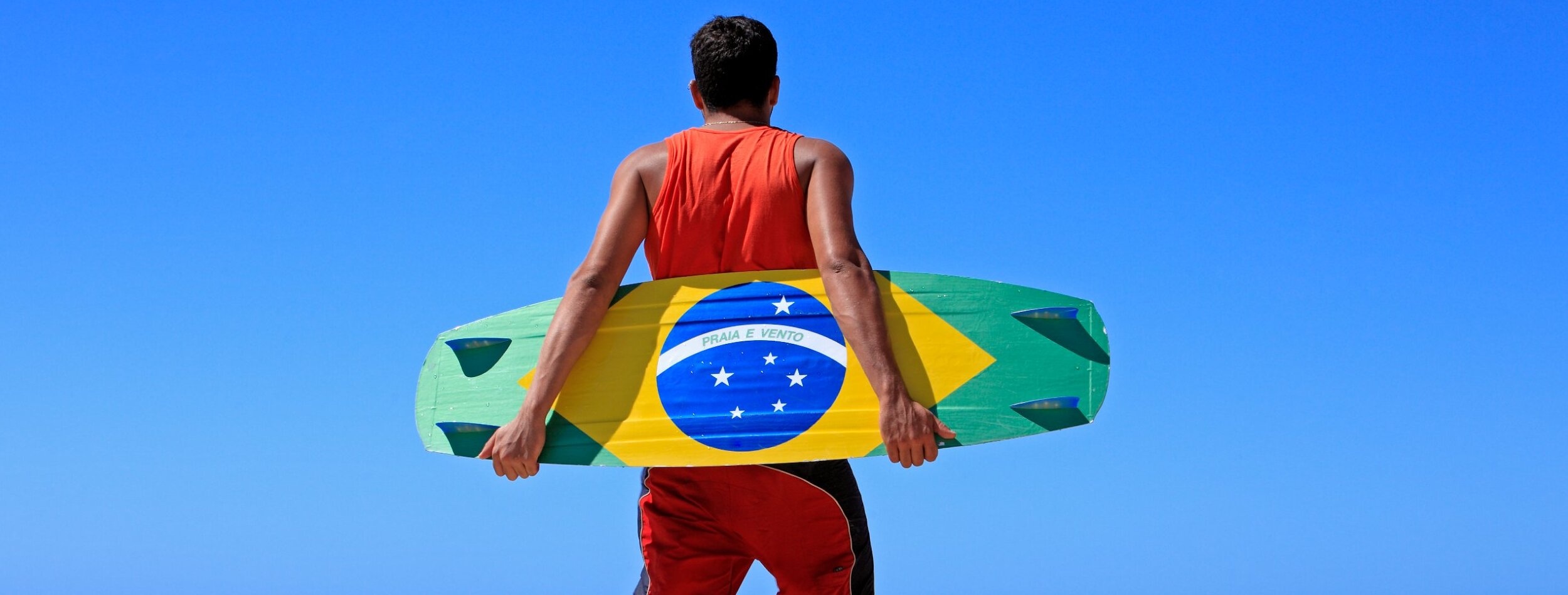 A guy showing a board with the brazil flag painted on.